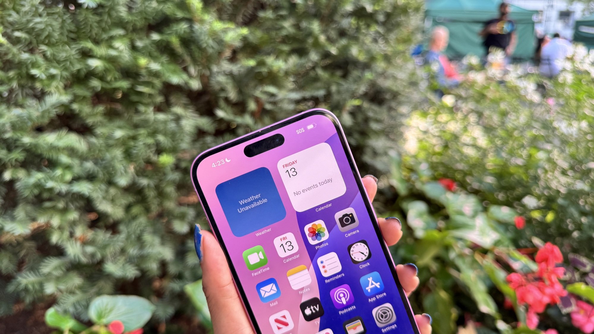 Woman holding the iPhone 16 in front of a bush