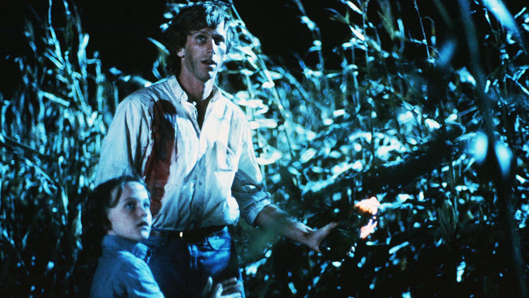 A man and a child stand in a cornfield.