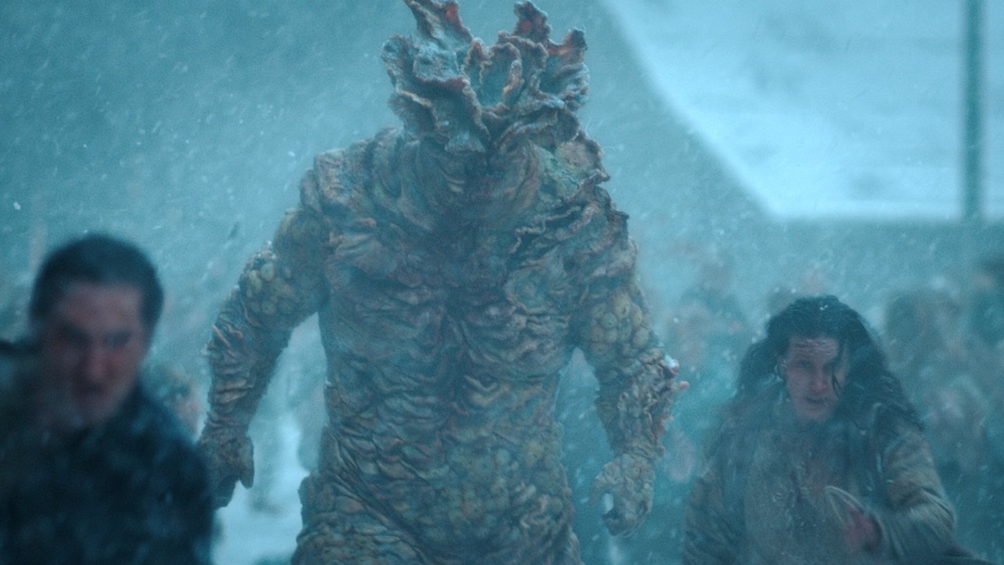 A giant Infected monster chases people through the snow in "The Last of Us."