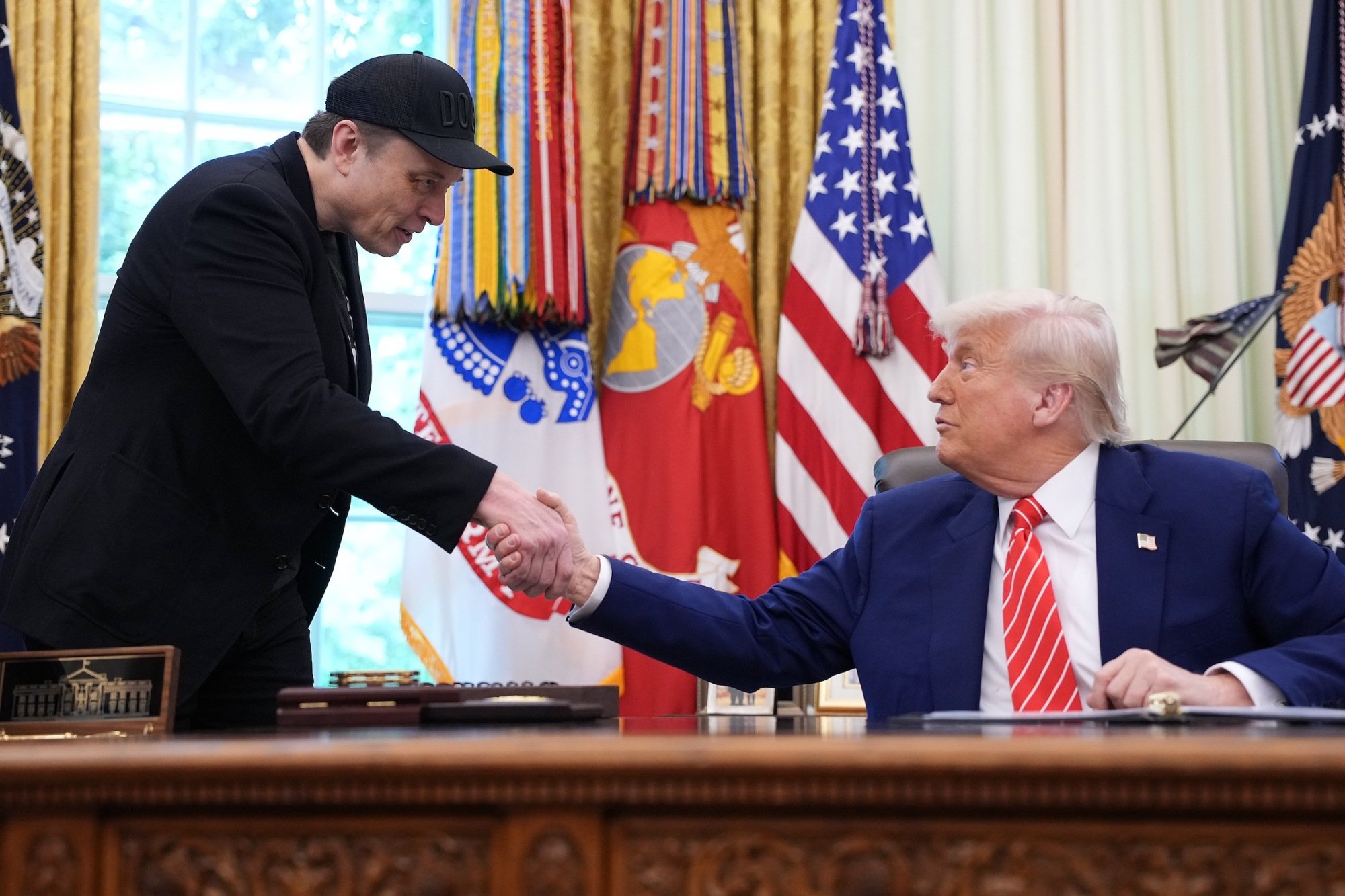 Tesla CEO Elon Musk shakes hands with President Donald Trump in the Oval Office